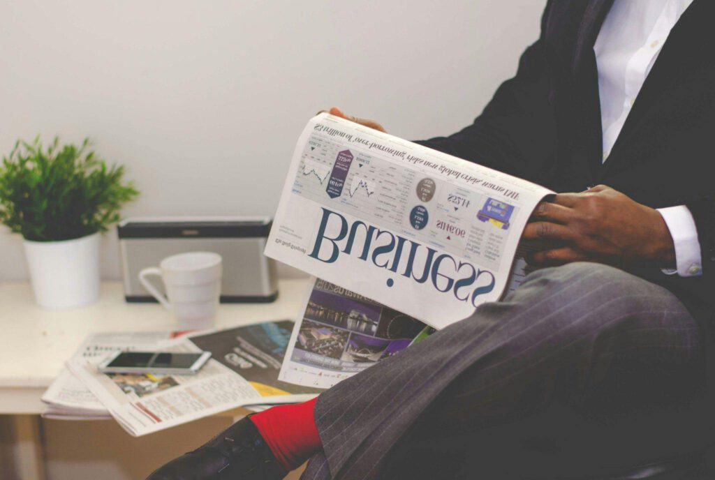 Businessman reading a financial newspaper at a desk, highlighting finance and commerce theme.